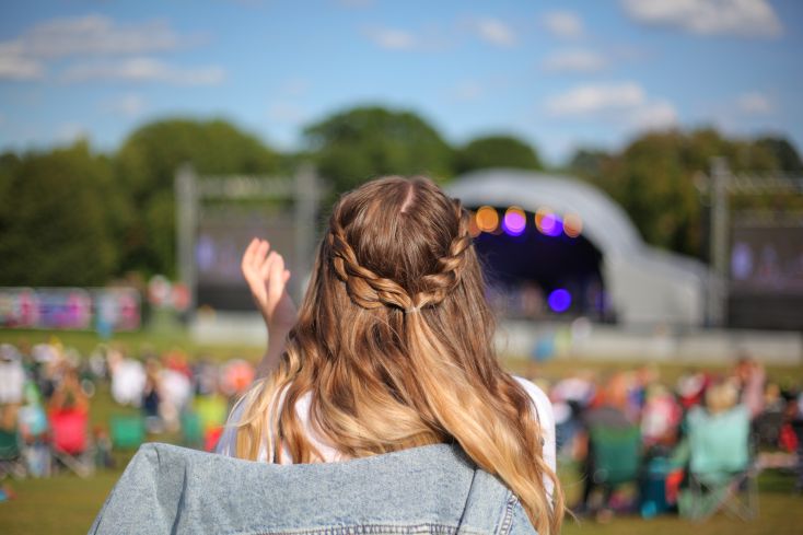 A person with long hair hair claps as they look on towards the Darley Park Concert stage